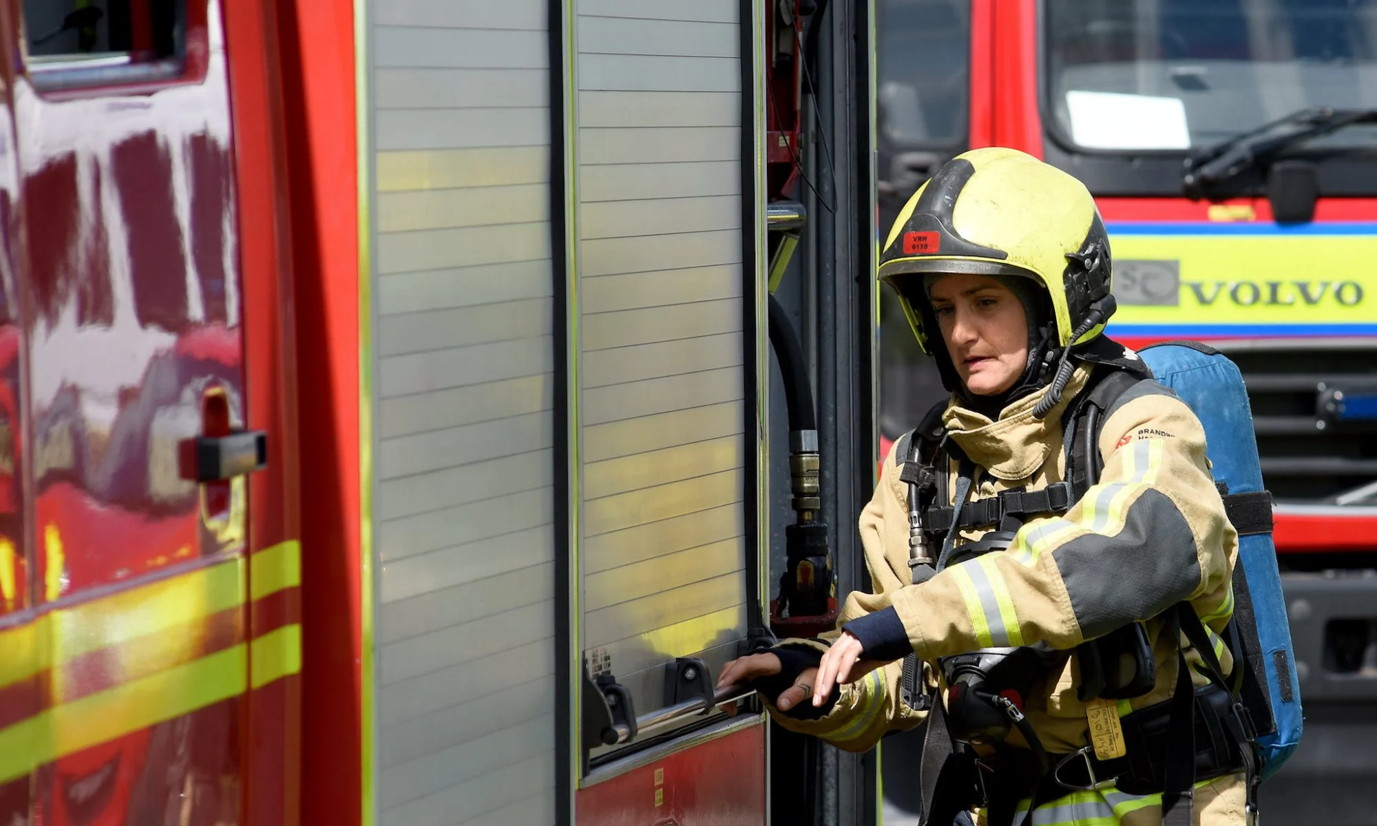 Firefighter opening the fire compartment on a fire appliance