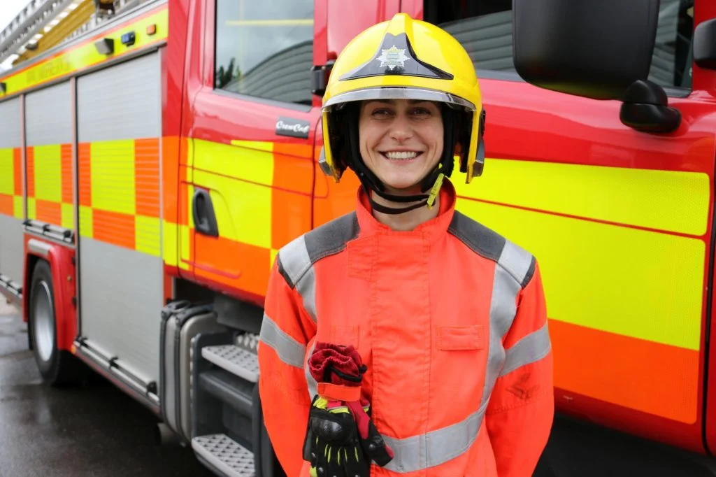 Firefighter Agata standing in front of the a fire appliance in her uniform