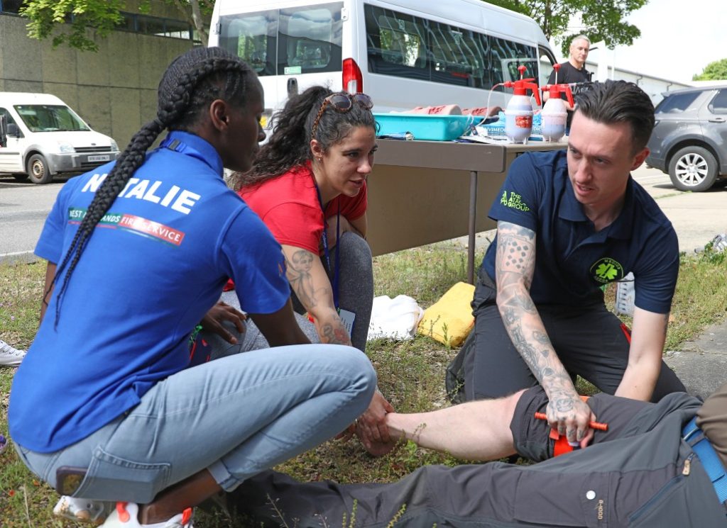 A man and two women carrying out casualty care on a person's leg during a training scenario
