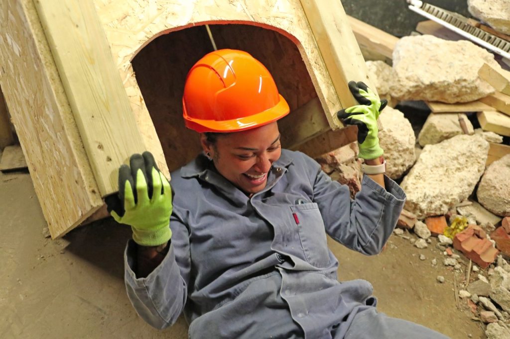 Woman in safety clothing lifting a wooden structure in an urban search and rescue training scenario