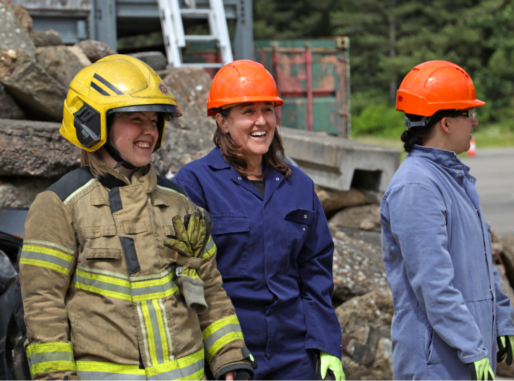 Three smiling women in fire and rescue safety wear on the training ground