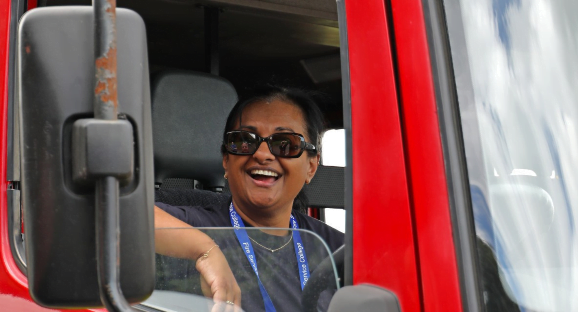 Woman smiling at the driving wheel of a fire appliance